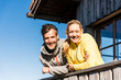© Westend61 - Couple leaning on balcony of a mountain hut, smiling