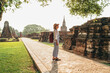 © Soloviova Liudmyla - Young backpacker tourist woman with modern mirrorless camera enjoying walking at ancient ruins during Asian vacation Ayutthaya Thailand historical Buddhist temple UNESCO heritage site sightseeing