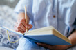 © Iryna - Handwriting in blue notebook, middle aged woman journaling at home
