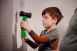 © Oleksii Yemelianov - Close-up side view of a child holding a rubber mallet against an interior wall during a home DIY task. Family renovation moment with practical learning and safe supervision.