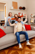© Maria Vitkovska - Portrait of beautiful family sitting on sofa hugging looking at camera at home in living room