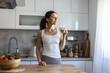 © Jelena Stanojkovic - Caucasian beautiful woman in sportswear drink water after exercise. Young thirsty active sport girl takes a sips of clean mineral natural in cup after workout for health care in kitchen in house.