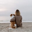 © Andrii Zastrozhnov - Young adult female sitting with dog on beach at sunset