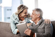 © peopleimages.com - Love, couple and relax with tablet in home for streaming, bonding and relationship attention. Support, mature people and happy with tech on sofa for internet browsing, affection and healthy marriage