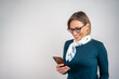 © Nenad - Mixed race businesswoman using smartphone isolated on grey wall