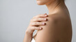 © rafiadadisini - High-quality close-up of a woman touching her smooth shoulder skin. Ideal for skincare, beauty products, and dermatological health branding.