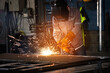 © chotiga - Welding welder spark metal steel workshop industrial factory plants technician fuses plate with arc as bright fire flashes and safety gear shields face and hand