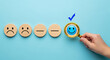 © SALMA1234 - Hand choosing happy face with magnifying glass from wooden emoticons