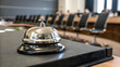 © MdRakibHasan - A silver service bell on a dark surface in a conference room with blurred chairs in the background