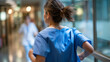 © Laura - Defocused blurred motion of faceless female nurse in blue scrubs running through hospital corridor during emergency, urgent response, critical care situation, medical staff