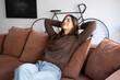 © luciano - Smiling relaxed serene pretty young woman feel fatigue lounge on comfortable sofa hands behind head rest at home. Concept of rest, wellbeing, and modern home lifestyle.