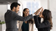 © fizkes - Three multinational happy teammates celebrate success, progress and career growth in office, exchanging high five gesture, enjoy project launch, task accomplishment. Triumph, achievement, team spirit