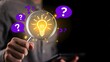© Anwesha Dey - Businessman holding magnifying glass with glowing light bulb and question marks, representing problem solving, finding solutions, critical thinking, and innovative decision making.