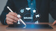 © MDTOFIZ - Businessman using a stylus on a tablet with a brand strategy icon circle branding marketing