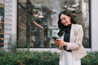 © Tj - Asian woman texting on smartphone in urban setting