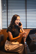 © Tj - Woman making phone call using tablet in office