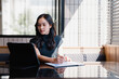 © Tj - Asian businesswoman working on tablet and analyzing documents in office