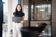 © Tj - Young asian businesswoman holding folder in modern office