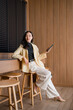 © Tj - Asian woman sitting bar stool using smartphone