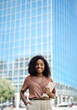 © insta_photos - Vertical portrait of happy confident young African American professional woman, student, female entrepreneur, businesswoman manager looking at camera holding tab standing on business city street.