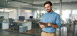 © insta_photos - Smiling busy young latin business man manager using tablet computer, happy hispanic businessman executive looking at tab device analyzing finance trading market data working standing in office.