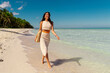 © Home-stock - Young woman walking barefoot on ocean shore on tropical beach, enjoying summer vacation and relax concept, paradise holidays