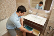 © Rychko Yevhen - Man putting dirty laundry into a storage basket in a bathroom drawer