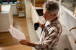 © Marko Geber - Mature man reading bills with coffee in home kitchen