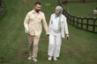 © Malik Nalik - A happy couple holding hands in a lush green park, enjoying a romantic moment together, a pregnant woman in hijab, and a man with a broken arm, outdoor love story, connection, happiness, nature.