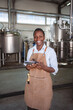 © Jelena - Black woman working in a brewery using digital tablet