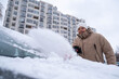 © phpetrunina14 - Man Clearing Snow from Car in Winter Cityscape Copy Space