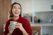 © Jelena - Happy young asian woman laughing holding coffee mug