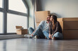 © Daniel - Cheerful dreamy girl and guy relaxing at new home after moving, relocation activities, sitting at paper boxes, looking at window away, thinking, dreaming of modern interior in renovated apartment