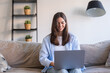 © Daniel - Concentrated millennial girl sit on couch working on laptop browsing internet at home during lazy weekend, focused young woman freelancer busy using computer surfing wireless web shopping online