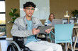 © Wavebreak Media - Diverse coworkers sitting in workspace with wheelchair using tablet and laptop near whiteboard
