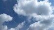 © Nabil - White fluffy cumulus clouds and some darker grey clouds drift across a clear blue sky on a sunny day, creating a beautiful natural background.