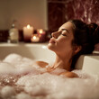 © halcon1 - Female in a bubble bath relaxing with closed eyes, soft lighting from candles illuminating the bathroom with marble accents and a serene atmosphere