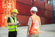 © Wanwajee - Industrial managers reviewing cargo records and giving operational directions among stacked shipping containers.