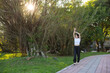 © leungchopan - Woman stretching her arm while walking in park
