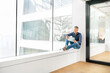 © Westend61 - Casual businessman sitting on windowsill in office building, using laptp