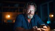 © svastix - A smiling man with a beard enjoys looking at his smartphone in a cozy indoor setting, illustrating the connection between technology and personal joy in modern life.