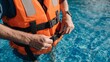 © t.sableaux - Hands fastening straps on an orange life vest in a sparkling blue pool, showcasing summer fun and safety in a vibrant aquatic setting