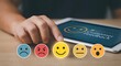 © Yuliia - Customer feedback rating concept with colorful emoji faces from sad to happy on wooden desk next to tablet showing satisfaction survey interface.