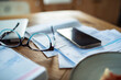 © Geber86 - Household bills, smartphone, and glasses on a wooden kitchen table