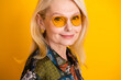 © deagreez - Elegant mature woman with yellow sunglass poses on a vibrant yellow background wearing scarf and gold jewelry for a stylish fashion lifestyle stock photo