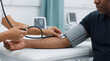 © Eduardo Accorinti - Female healthcare worker taking blood pressure on an adult male patient in a medical clinic, close-up with cropped faces