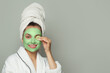 © artmim - Joyful woman in green organic cosmetic face mask holding cucumber slices