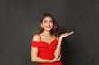 © artmim - Joyful model woman holding empty open palm hand and looking up on black background