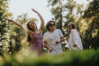 © qunica.com - Three young adults dance in a sunny park, smiling and enjoying a carefree outdoor moment.