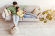 © Prostock-studio - Loving Asian couple using smartphone, surfing internet or watching movie online, resting on sofa in living room, top view. Young husband and wife with mobile device chilling at home. Free space